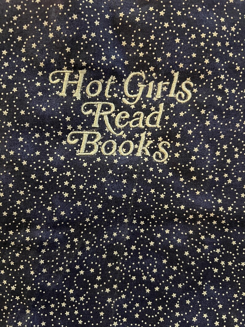 Puede incluir: Tela azul marino con un patr&oacute;n de estrellas blancas. La frase "Hot Girls Read Books" est&aacute; bordada en una fuente cursiva. La tela tiene una textura suave y aterciopelada.