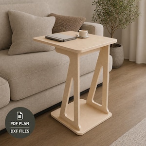 May include: A light-colored wooden C-shaped side table with a flat square top and a sturdy base. The table features a cutout design on the side supports. A small notebook and a white ceramic cup are placed on the surface. Includes PDF plan and DXF files.