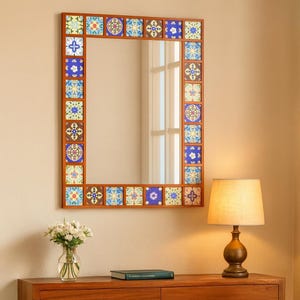 Può includere: Specchio da parete quadrato con cornice in legno e piastrelle decorative in ceramica blu, gialle e marroni. Lo specchio è rettangolare e riflette la stanza. Le piastrelle hanno motivi floreali e geometrici.