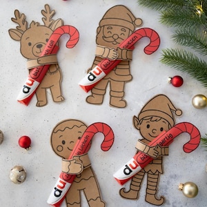 Könnte beinhalten: Vier weihnachtliche Papierschnitte: ein Rentier, der Weihnachtsmann, ein Lebkuchenmann und ein Elf, die jeweils eine rot-weiße Zuckerstange halten. Die Zuckerstangen haben Text darauf. Weihnachtsdekorationen sind verstreut.