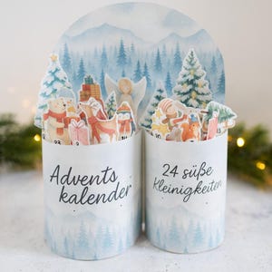 Peut inclure: Calendrier de l'Avent de Noël avec deux contenants cylindriques décorés d'une scène hivernale et remplis de figurines festives. L'arrière-plan présente une illustration à l'aquarelle d'une forêt enneigée et de montagnes. Le texte indique "Adventskalender" et "24 süße Kleinigkeiten."
