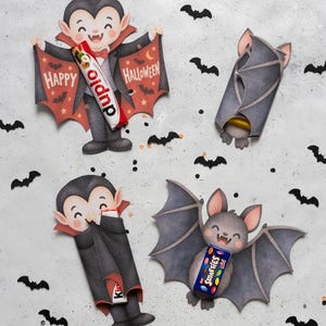 Könnte beinhalten: Zwei Vampir- und zwei Fledermaus-Papieraufsteller, dekoriert mit kleinen schwarzen Fledermaus-Konfetti. Ein Vampir hält einen Duplo-Riegel, ein anderer einen Kinder-Riegel und eine Fledermaus hält eine Schachtel Smarties in den Händen.