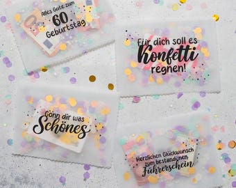Op de afbeelding: Vier transparante cellofaan cadeauzakjes met confetti en tekst. Eén zakje zegt "Alles Gute zum 60. Geburtstag" met geld erin. Een ander zegt "Für dich soll es Konfetti regnen!". De derde zegt "Gönn dir was Schönes". De laatste zegt "Herzlichen Glückwunsch zum bestandenen Führerschein".