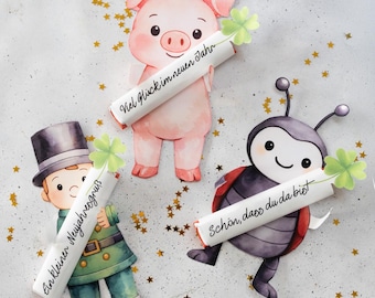 May include: Three whimsical paper cutouts: a pig, a chimney sweep, and a ladybug, each holding a scroll with German text. The pig is pink, the chimney sweep wears green and black, and the ladybug is red and black. Gold star confetti.