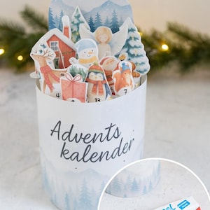 Può includere: Un calendario dell'Avvento bianco con una scena invernale e la scritta "Adventskalender". Il calendario presenta ritagli di una casa, un angelo, un pupazzo di neve, un pinguino e altre figure festive. Una barretta di cioccolato Kinder Riegel si trova nell'angolo in basso a destra.