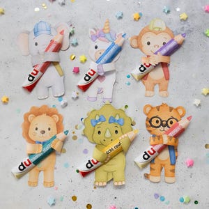 Peut inclure: Six figurines d'animaux en papier découpé représentant un éléphant, une licorne, un singe, un lion, un tricératops et un tigre. Chaque personnage tient un crayon de couleur avec le texte "du" imprimé. Des confettis en forme d'étoiles entourent le tout.