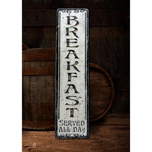 May include: A white wooden sign with black lettering that reads "BREAKFAST SERVED ALL DAY". The sign is distressed and has a rustic look.