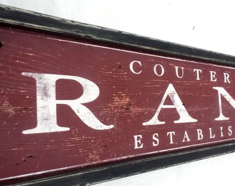 May include: A rustic wooden sign with black trim and red paint. The sign reads "Coutermarsh Ranch Established 2017".