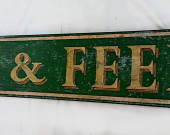 Può includere: Un cartello in legno vintage con vernice verde e lettere dorate che recita "Grocery & Feed".