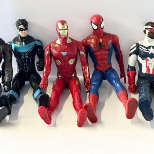 Puede incluir: Se muestran cinco figuras de acci&oacute;n de superh&eacute;roes, incluyendo Iron Man, Spider-Man y Capit&aacute;n Am&eacute;rica. Las figuras est&aacute;n en posici&oacute;n sentada con las piernas extendidas. La paleta de colores incluye rojo, azul, negro y plateado.