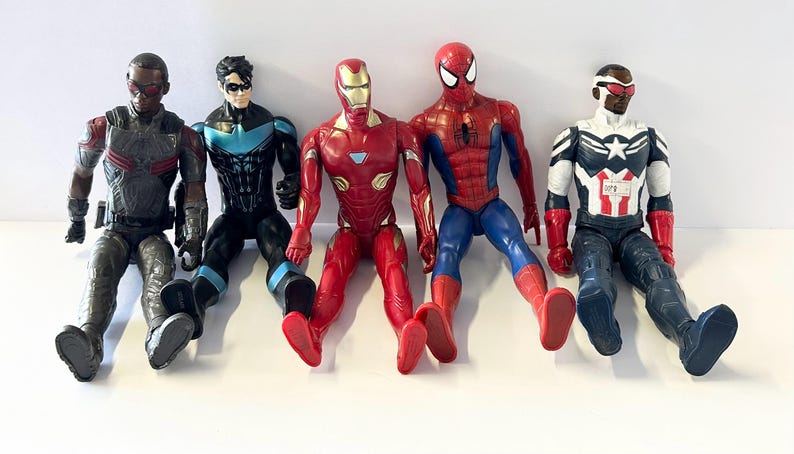 Puede incluir: Se muestran cinco figuras de acci&oacute;n de superh&eacute;roes, incluyendo Iron Man, Spider-Man y Capit&aacute;n Am&eacute;rica. Las figuras est&aacute;n en posici&oacute;n sentada con las piernas extendidas. La paleta de colores incluye rojo, azul, negro y plateado.