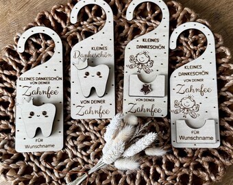 May include: Four wooden tooth fairy door hangers with various designs. Each hanger has a curved top for hanging and features a tooth or fairy illustration, along with German text. One hanger has a small pocket for a tooth.