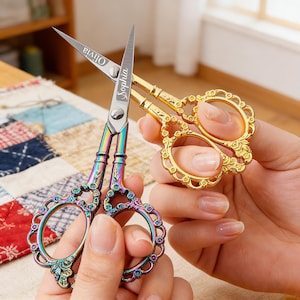 May include: Two pairs of decorative scissors. One pair has a rainbow finish with the name "Olivia" on the blade. The other pair is gold-toned. Both pairs have ornate handles. The name "Sophia" is on the blade of the rainbow scissors.