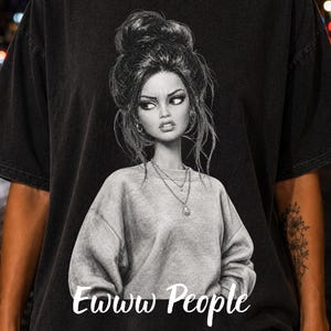 May include: A black short-sleeve t-shirt featuring a graphic illustration of a person with a messy bun hairstyle wearing a sweatshirt and layered necklaces. The text Ewww People is printed in white cursive lettering below the illustration.