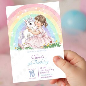 Puede incluir: Una invitaci&oacute;n de cumplea&ntilde;os con una ni&ntilde;a vestida de rosa besando a un unicornio bajo un arco&iacute;ris. La invitaci&oacute;n incluye el texto "Olivia's 5th Birthday" con los detalles del evento: fecha, hora y lugar.