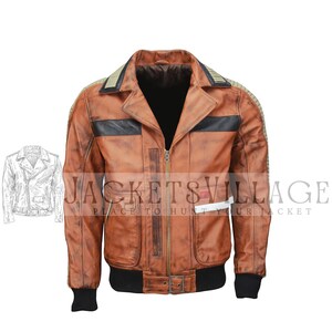 Könnte beinhalten: Braune Lederjacke mit Reißverschluss, schwarzen Akzenten und geripptem, schwarzem Saum und Bündchen. Die Jacke hat einen Kragen und einen kleinen weißen rechteckigen Aufnäher. Der Text "JACKETS VILLAGE PLACE TO HUNT YOUR JACKET" ist sichtbar.