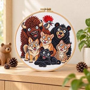 Könnte beinhalten: Ein runder Stickrahmen aus Holz mit einem Kreuzstichmuster, das eine Gruppe nordamerikanischer Tiere zeigt, darunter ein brauner Bison, ein Schwarzbär, ein Puma, ein Wolf, ein schwarzer Panther, ein Luchs und ein Helmspecht.