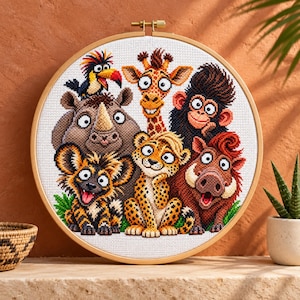Puede incluir: Un bastidor de bordado circular de madera que contiene un patrón de punto de cruz de un grupo de animales de la sabana africana, incluyendo un rinoceronte, jirafa, mono, leopardo, hiena, jabalí y un pájaro colorido sobre tela blanca.