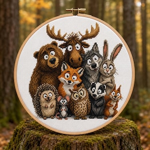 Puede incluir: Un bastidor de bordado circular de madera que contiene un patrón de punto de cruz de un grupo de animales del bosque, incluyendo un oso pardo, un alce, un zorro, un lobo, un conejo, un erizo, un ratón, un búho, un tejón y una ardilla.