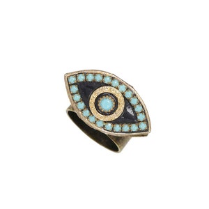 May include: A gold-tone ring with a blue and black evil eye design. The eye is surrounded by turquoise-colored beads.