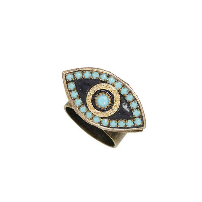 May include: A gold-tone ring with a blue and black evil eye design. The eye is surrounded by turquoise-colored beads.