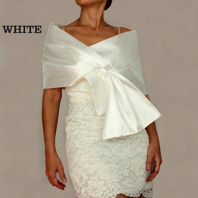 White lace dress with a white sheer shawl tied in a bow at the front. The shawl is made of a lightweight fabric and has a delicate sheen.