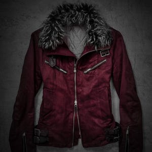 Op de afbeelding: Bordeaux jas met een kraag van imitatiebont. De jas heeft een ritssluiting, meerdere zakken met ritssluiting en gespen op de mouwen en taille. De voering is gewatteerd.