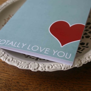 May include: A light blue card with a red heart and the text "I totally love you".
