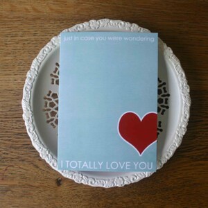 May include: A light blue card with the text "just in case you were wondering" and "I TOTALLY LOVE YOU". A red heart is in the center of the card.
