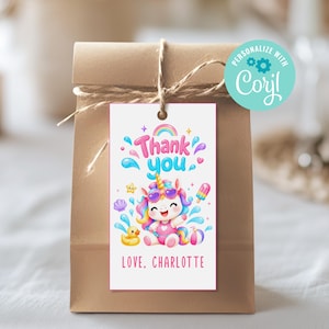 Può includere: Un sacchetto regalo di carta marrone con un'etichetta che dice "Thank you" e "Love, Charlotte". L'etichetta presenta un unicorno dei cartoni animati con occhiali da sole, un arcobaleno e spruzzi d'acqua. Un'anatra di gomma gialla e un ghiacciolo sono anche sull'etichetta.