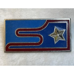 May include: A rectangular metal pin featuring a blue enamel background with a prominent silver-toned star on the right side. A continuous, winding maroon enamel stripe curves across the left and center, framed by a thin silver metal border.