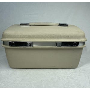 May include: A rectangular, off-white hard-shell vanity case with a textured exterior. The case features a top handle, a silver-toned metal band around the center, and two latch closures. One latch displays the letter K in a square emblem.