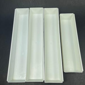 May include: Four rectangular white plastic storage trays arranged side by side. Three of the trays are of equal length, while the fourth tray on the far right is shorter in length. Each tray features a smooth, open-top design with straight walls.