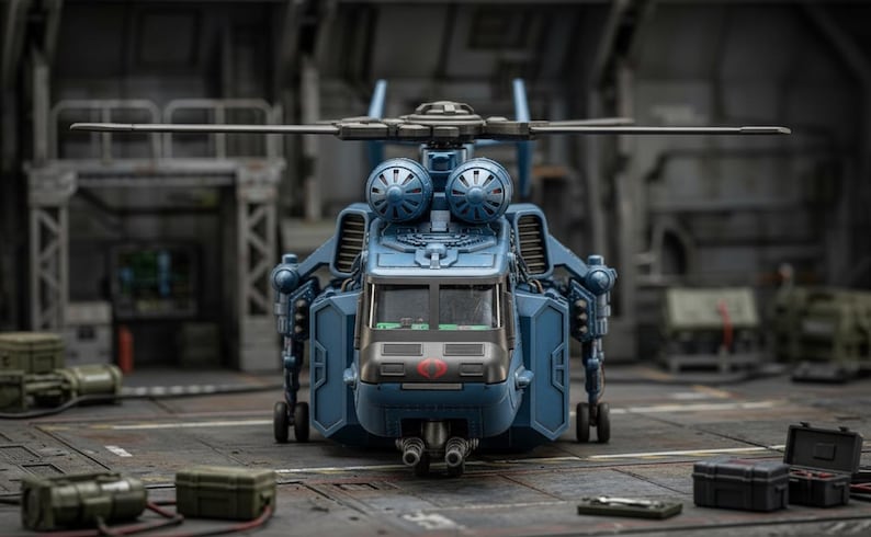 Pu&ograve; includere: Un elicottero giocattolo blu con un design dettagliato, con cabina di pilotaggio, rotori e vari componenti meccanici. Il giocattolo &egrave; ambientato sullo sfondo di un hangar o di un ambiente industriale, con altri accessori giocattolo in primo piano.