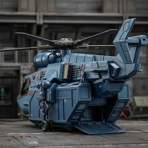 Pu&ograve; includere: Un modello dettagliato di elicottero giocattolo blu dal design complesso. Il modello presenta un rotore principale, un rotore di coda e un portellone di carico posteriore. L'elicottero &egrave; ambientato su uno sfondo industriale.