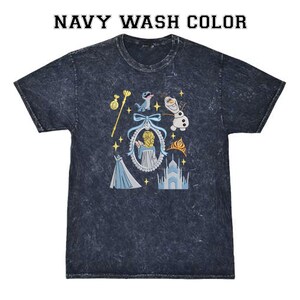 May include: Navy wash colour t-shirt with a graphic featuring characters and elements from a popular animated film. The design includes a castle, a dress, and a snowman. The text "NAVY WASH COLOR" is at the top.