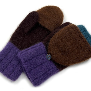 Può includere: Un paio di guanti a muffola lavorati a maglia nei toni del marrone, viola e verde acqua. I guanti hanno una chiusura con bottone e un polsino a coste. Il design presenta sezioni a blocchi di colore, creando un accessorio accogliente.