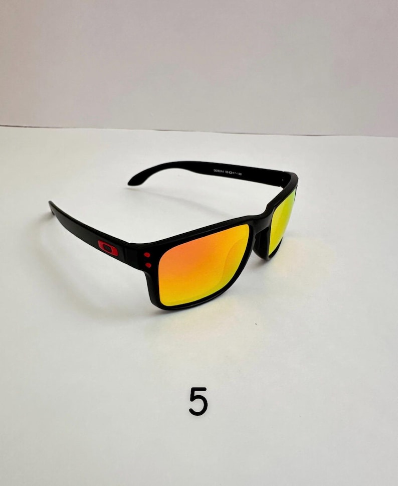 May include: Black sunglasses with orange mirrored lenses. The sunglasses have a rectangular frame with a red logo on the side. The lenses reflect a bright orange color. The number "5" is printed in black below the sunglasses.