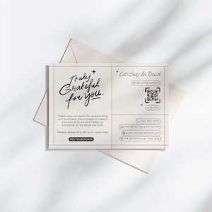 May include: A cream-coloured thank you card with the text "Truly Grateful for You" in a handwritten style. The card includes a QR code, social media handle, and contact information. The card is on top of a cream-coloured envelope.