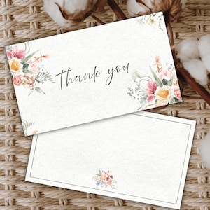 Peut inclure: Deux cartes de remerciement blanches avec des motifs floraux. La carte du haut porte l'inscription "thank you" en écriture cursive. Les cartes présentent des compositions florales à l'aquarelle roses, pêche et vertes. La carte du bas a une bordure grise.