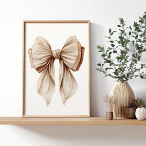 Peut inclure: Impression d'art encadr&eacute;e d'un grand n&oelig;ud &eacute;l&eacute;gant dans des tons beige et marron. Le n&oelig;ud est centr&eacute; sur un fond blanc, avec des ombres d&eacute;taill&eacute;es pour un rendu r&eacute;aliste. L'&oelig;uvre est expos&eacute;e sur une &eacute;tag&egrave;re en bois avec des vases d&eacute;coratifs et de la verdure.