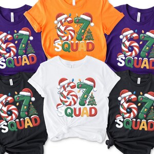 May include: A collection of short-sleeved t-shirts in various colors, including purple, orange, white, and black. Each shirt features a festive design with the number "67" decorated with candy canes and Christmas lights, along with the word "SQUAD".