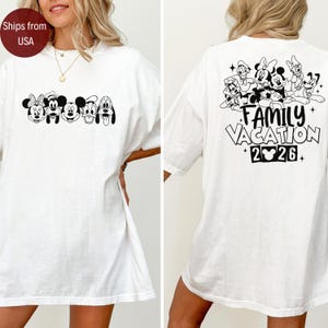 May include: White t-shirt featuring a black and white graphic of Disney characters on the front. The back of the shirt displays a group of Disney characters above the words "Family Vacation 2026."
