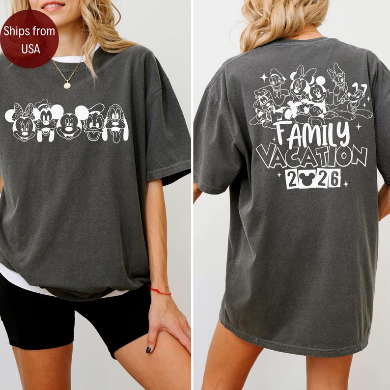 May include: Dark gray t-shirt featuring white cartoon character graphics on the front and back. The front displays several characters, while the back says "Family Vacation 2026" with character graphics. The shirt has a relaxed fit.