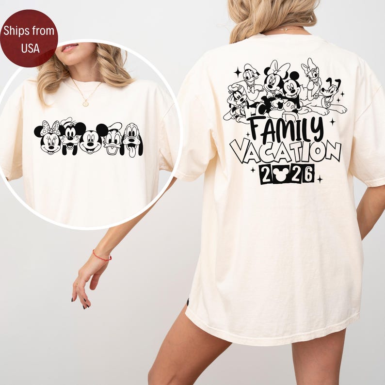 May include: Cream-colored t-shirt featuring a black and white graphic of Disney characters on the front and back. The front displays Mickey, Minnie, Donald, Goofy, and Pluto. The back says "FAMILY VACATION 2026".