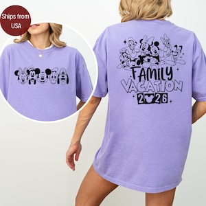 May include: A lilac-colored t-shirt featuring a black graphic of Disney characters on the front and back. The back of the shirt displays the text "FAMILY VACATION 2026" with additional character illustrations. The shirt has a relaxed fit.