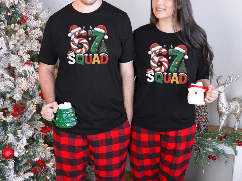 May include: Matching black t-shirts with a festive "67 SQUAD" design, candy cane-style numbers, and Christmas tree graphics. Paired with red and black plaid pajama pants. One person holds a green tree mug, the other a Santa mug.