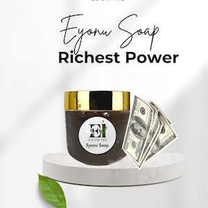 May include: A jar of Ebon Ire Eyonu Soap with a gold lid, set on a white pedestal. The label features the brand's logo and the words "Eyonu Soap." Three US $100 bills are next to the jar. The text "Richest Power" is above the jar.