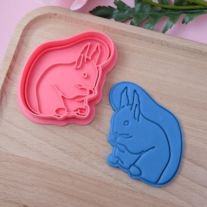 May include: Two cookie cutters shaped like squirrels. One is pink and the other is blue.