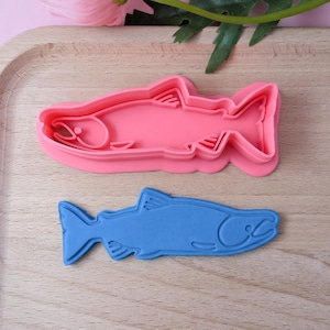 Könnte beinhalten: Zwei Silikon-Ausstecher in Form von Lachs. Der größere Ausstecher ist rosa und der kleinere ist blau.